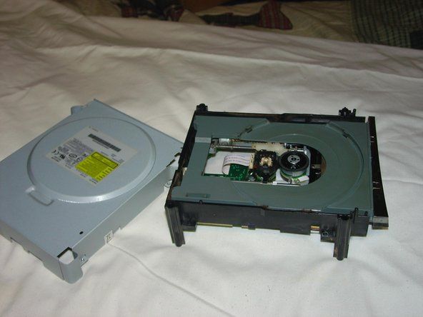 ネジを外し、DVDドライブの側面にあるセキュリティステッカーをカットまたははがします（保証も無効になります）。下部と上部の金属ケースを持ち上げて外します。' alt=