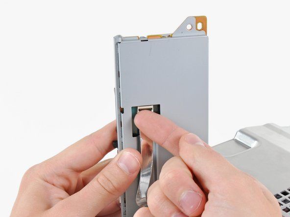 Wyjmij czytnik kart pamięci z PS3 na tyle, aby uzyskać dostęp do kabla taśmowego.' alt=