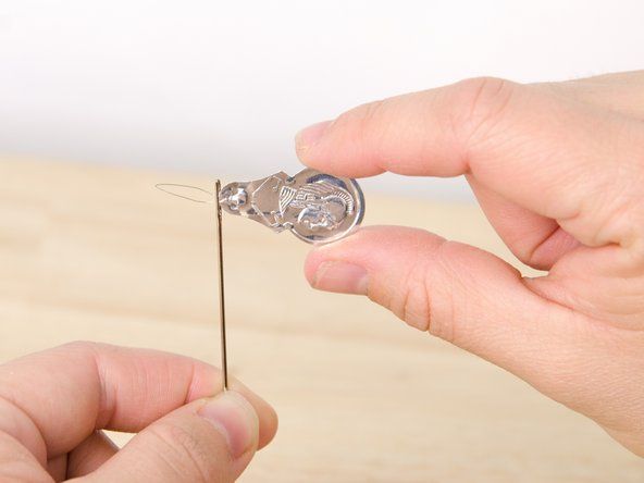 針の目を通して針糸通し器にワイヤーループを挿入します。' alt=