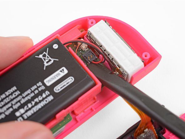 Bruk en spudger for å lirke batterikontakten forsiktig rett opp fra kontakten på hovedkortet. Dette vil forhindre at Joy-Con slås på under reparasjonen.' alt=