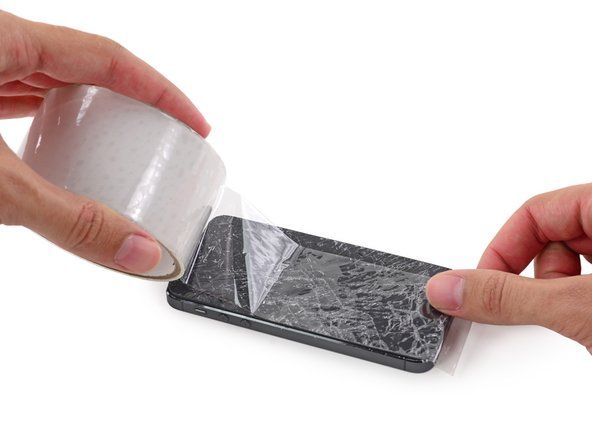 iPhoneの上に透明なパッキングテープの重なり合うストリップを置きます' alt=