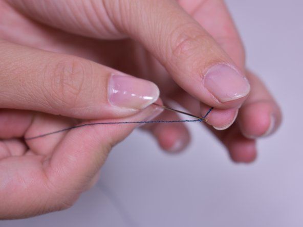 針が中央にぶら下がるまで、針を糸に滑り込ませます。針の両側に2つの等しい長さの糸が必要です。' alt=