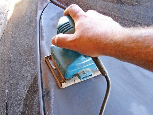 パワーサンダーと低グリットサンドペーパーを使用して、古い塗料を車両の表面から剥がします。小さな場所や入手困難な場所に到達するには、サンディングブロックまたはサンドペーパーだけを使用します。' alt=