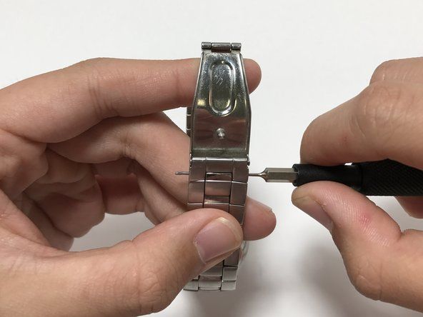 Entfernen Sie den Stift vom Uhrenarmband, um einen leichteren Zugang zur Rückseite der Uhr zu erhalten.' alt=