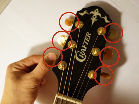 Za odvijanje kitare zasukajte 6 gumbov v ustreznih smereh.' alt=