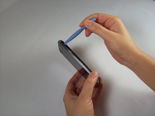 Rimuovere la cover posteriore del telefono cellulare utilizzando uno strumento di apertura in plastica.' alt=