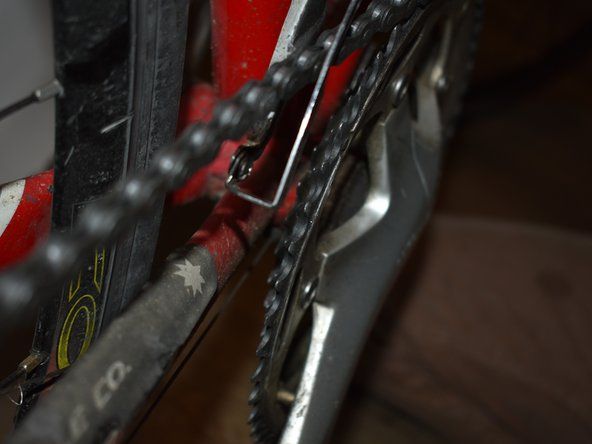 チェーンがまだ自転車に乗っている場合は、ディレイラーケージのテールスクリューを外し、ケージを曲げてチェーンを引っ張ります。次に、テールスクリューを再度取り付けて締めます。' alt=