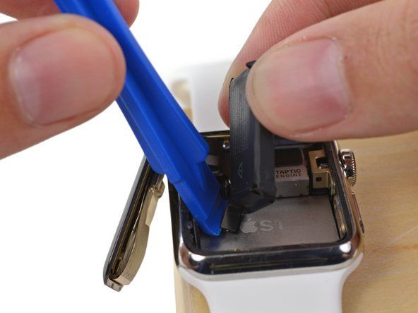 Użyj plastikowego narzędzia do otwierania, podważając spód obudowy, aby oddzielić złącze kabla baterii od zegarka' alt=