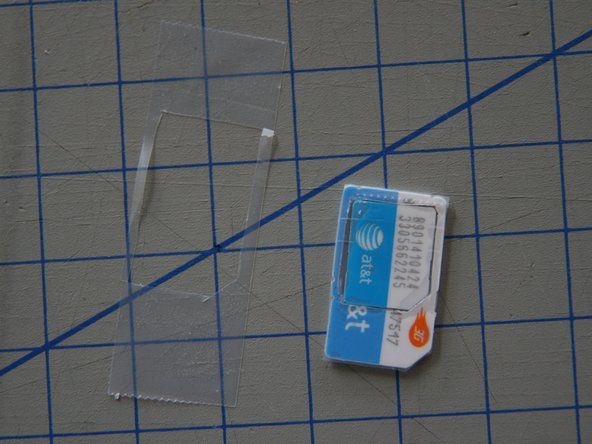 Jei skylę iškirpote šiek tiek per didelę, uždėkite juostos gabalėlį ant SIM kortelės galo (šone be auksinių kontaktų), kad „Micro-SIM“ būtų laikoma vietoje. Peiliu nupjaukite juostos perteklių.' alt=