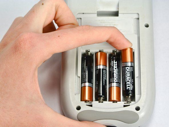 Skyv fra den positive siden til den negative siden og trekk opp for å ta ut hvert batteri.' alt=