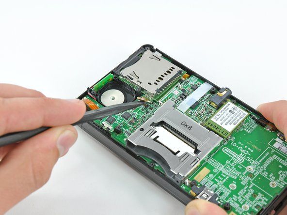 Utilisez l'extrémité plate d'un spudger pour faire levier sur le connecteur de la nappe de la carte SD de sa prise sur la carte mère.' alt=