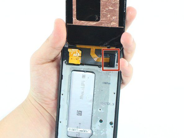 ガラスが外れると、電話の上部にあるマザーボードへの画面接続を覆う小さなクリップが表示されます。ピンセットを使用して、クリップの側面の折り目をつかんで引き出します。' alt=