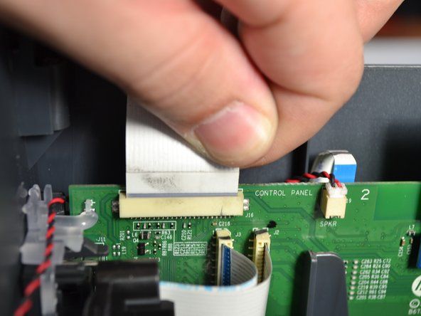 Pegang bagian dasar kabel pita putih yang menghubungkan penutup ke bagian bawah printer dan tarik keluar.' alt=