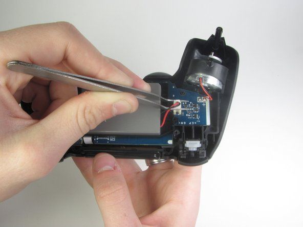 Använd den trubbiga tången för att ta bort batterikontakten genom att försiktigt gunga pincetten sida vid sida för att lossa kontakten.' alt=