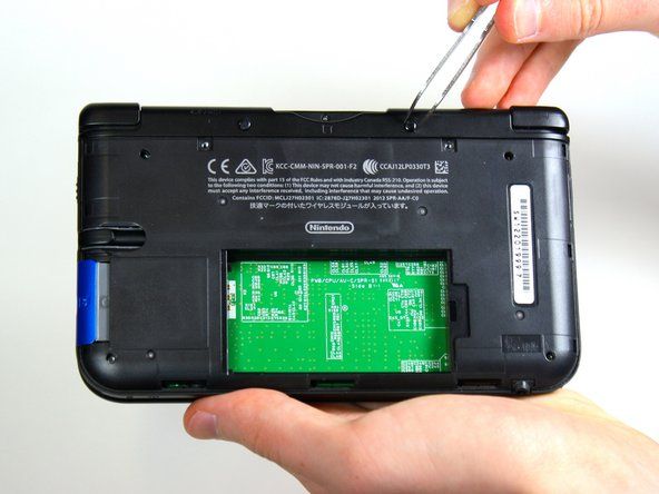 ピンセットを使用して、ゲームカートリッジコンパートメントの両側にあるデバイスの上部にあるゴム製のバンパーを引き出します。' alt=