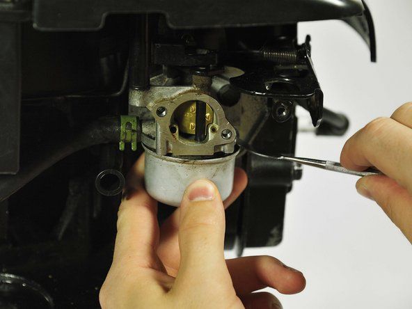 Kui polt on karburaatori paagi põhjast eemaldatud, avage paak ettevaatlikult metallist uuritava pihustiga, kuni see hüppab. Kui teil pole spuderit, töötab lamedakruvikeeraja.' alt=