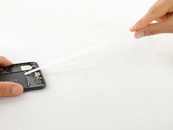 Lėtai traukite vieną akumuliatoriaus lipnią juostelę nuo akumuliatoriaus, link „iPhone“ apačios.' alt=