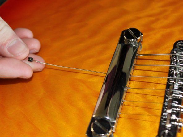 Verwijder de afgeknipte snaar van de brug van de gitaar en de bijbehorende spaak.' alt=