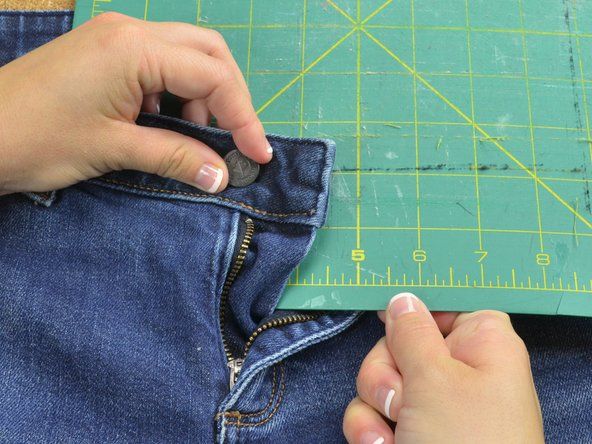 Letakkan permukaan kerja yang rata seperti sekeping kayu atau papan pemotong tepat di bawah tali dan antara bahagian depan dan belakang seluar jeans.' alt=