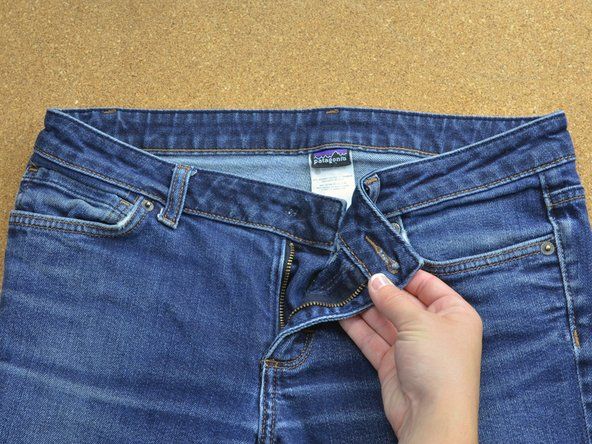 Buka zip dan buka seluar jeans di tali pinggang untuk menampakkan lubang di mana butang hilang.' alt=