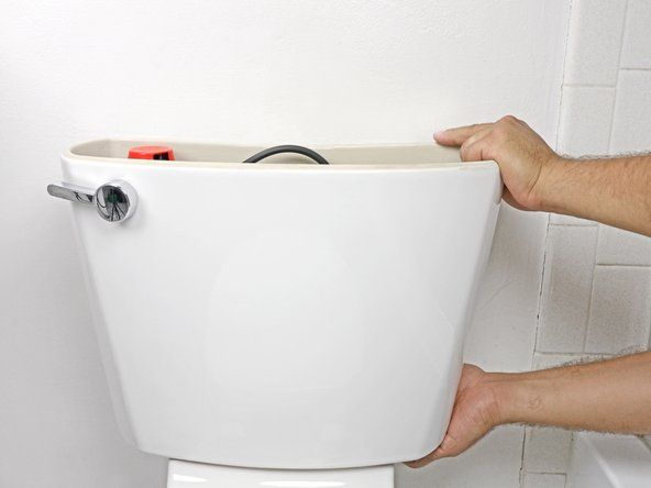 शौचालय के निचले आधे हिस्से से टैंक को ऊपर उठाएं।' alt=