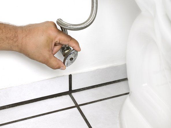 Utseendet til denne ventilen kan variere fra toalett til toalett, men de fleste fungerer likt. Noen ventiler krever flere svinger for å stoppe vannet, mens andre bare krever en kvart omdreining.' alt=