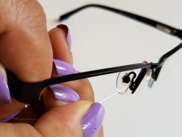 Włóż jeden koniec drutu do otworu w pobliżu ramienia elektrody i włóż drugi koniec po przeciwnej stronie okularów, a następnie zawiąż węzeł, jak pokazano na obrazkach.' alt=
