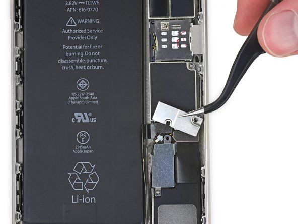 Ta bort metallbatteriets kontaktfäste från iPhone.' alt=