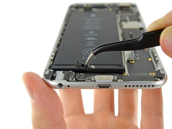 Sử dụng một chiếc nhíp để nắm kẹp nhựa nằm ở bên phải của giắc cắm tai nghe và tháo nó ra khỏi iPhone.' alt=