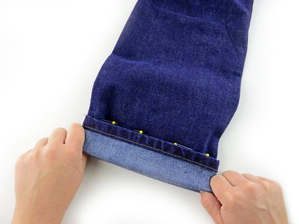 Pliez le poignet de la jambe du pantalon pour rencontrer la ligne d'épingles, en faisant correspondre le bord du jean avec la rangée d'épingles.' alt=