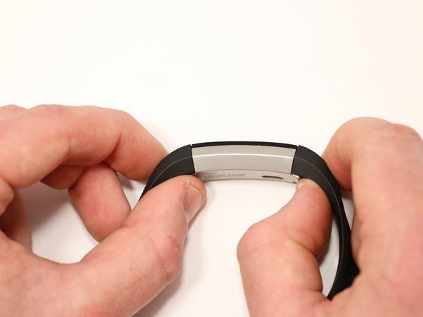 Pour libérer un loquet, appuyez sur le bouton métallique plat qui maintient le bracelet sur le Fitbit Alta. Tirez sur le loquet pour libérer la bande du corps.' alt=