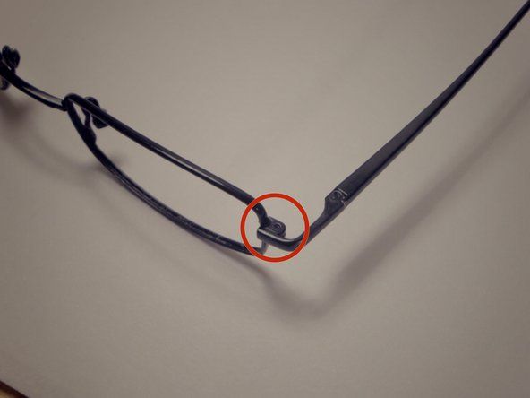 Пронађите вијак на угаоном шарки наочара између сочива и кракова и одврните га помоћу одвијача од 1,5 мм ротирањем у смеру супротном од казаљке на сату.' alt=