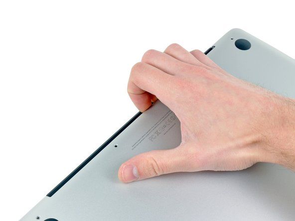 Gunakan jari anda untuk melepaskan sarung bawah dari badan MacBook berhampiran bolong.' alt=
