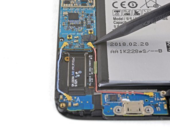 スパッジャーの先のとがったエッジを使用して、BluetoothおよびWi-Fiアンテナケーブルコネクタをマザーボードのソケットから外します。' alt=