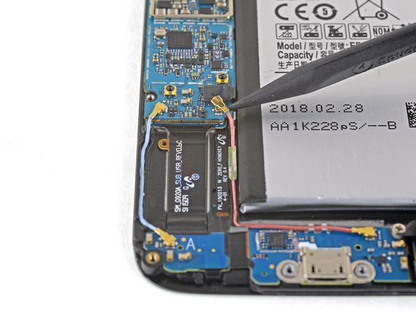 スパッジャーの先のとがったエッジを使用して、BluetoothおよびWi-Fiアンテナケーブルコネクタをマザーボードのソケットから外します。' alt=