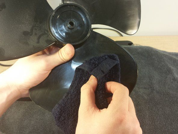 Fukta tvättduken med varmt vatten och börja torka ner knivarnas yta. Använd aldrig bensin, bensen eller thinner för att rengöra fläkten. Detta kommer att skada fläktens yta.' alt=