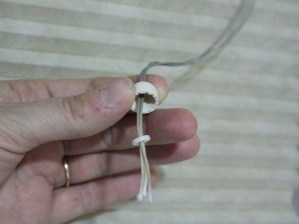 Fai scorrere la metà superiore della nappa sulle estremità delle corde e lega insieme le estremità.' alt=