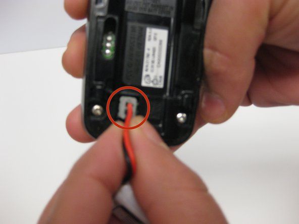 Távolítsa el a piros-fekete vezetékes portot a csatlakozóból közvetlenül az elemtartó rekesz alatt.' alt=