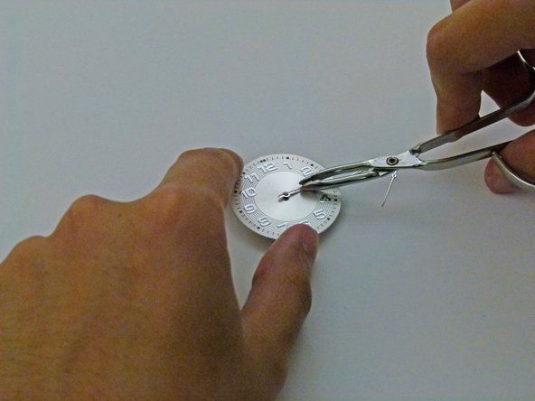 Pomocí pinzety umístěte hodinovou ručku do středu hodinek.' alt=