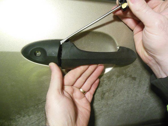 Fjern det utvendige dørhåndtaket ved å lirke forsiktig med en skrutrekker for å løsne, og skyv den deretter tilbake.' alt=