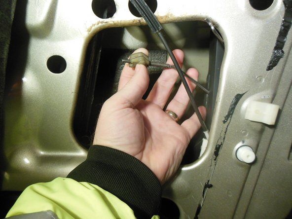Fjern dørlåsestangen fra håndtagets beslag ved at trække plastenden ud af metalsløjfen.' alt=