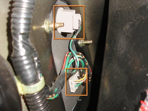 Localitzeu els dos connectors de llum del darrere del panell situats entre el revestiment i el conjunt de la llum del darrere del panell.' alt=