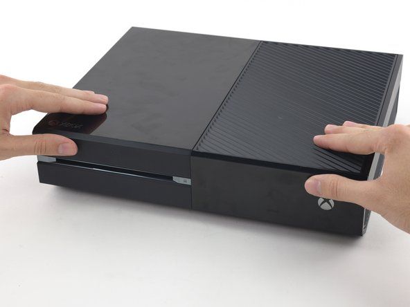 Työnnä etupaneelin yläosa Xboxiin, kuten sulkemalla postilaatikko. Paina lujasti niin, että etupaneelin yläkoteloon kiinnittävät pidikkeet lukittuvat kunnolla.' alt=