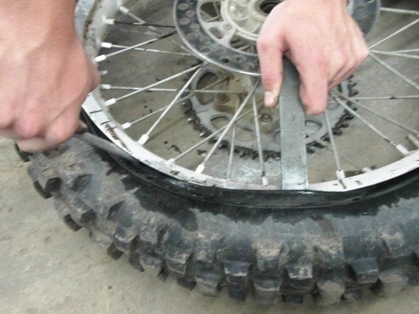Tada paimkite nešvarių dviračių padangų geležį ir pleištą tarp ratlankio ir padangos. Kai pleištas yra pritvirtintas, naudokite svirtį nuo ratlankio, kad patrauktumėte padangą aukštyn ir tolyn.' alt=