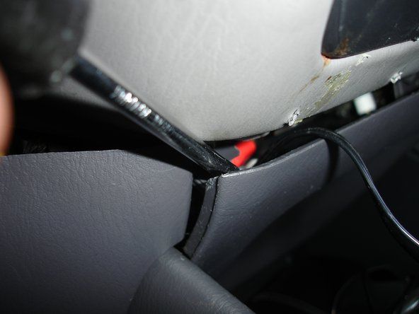 Bruk en flat skrutrekker for å lirke av venstre side av panelet rett under radioen.' alt=